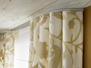 Gemusterter Vorhang fällt bündig von einer an der Decke montierten Aluschiene