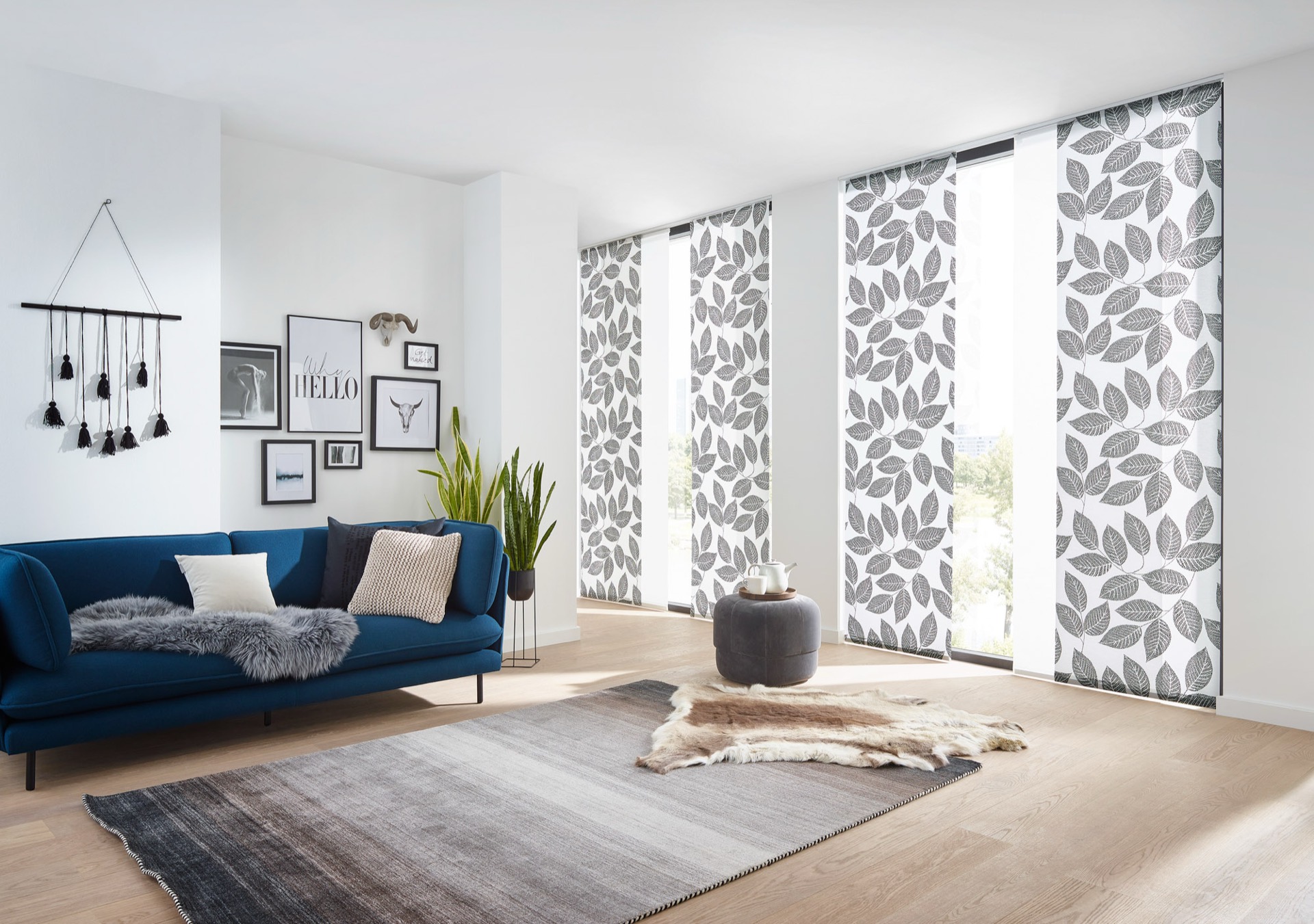 Flächenvorhang mit grossem Blattmuster in Wohnzimmer mit blauem Sofa