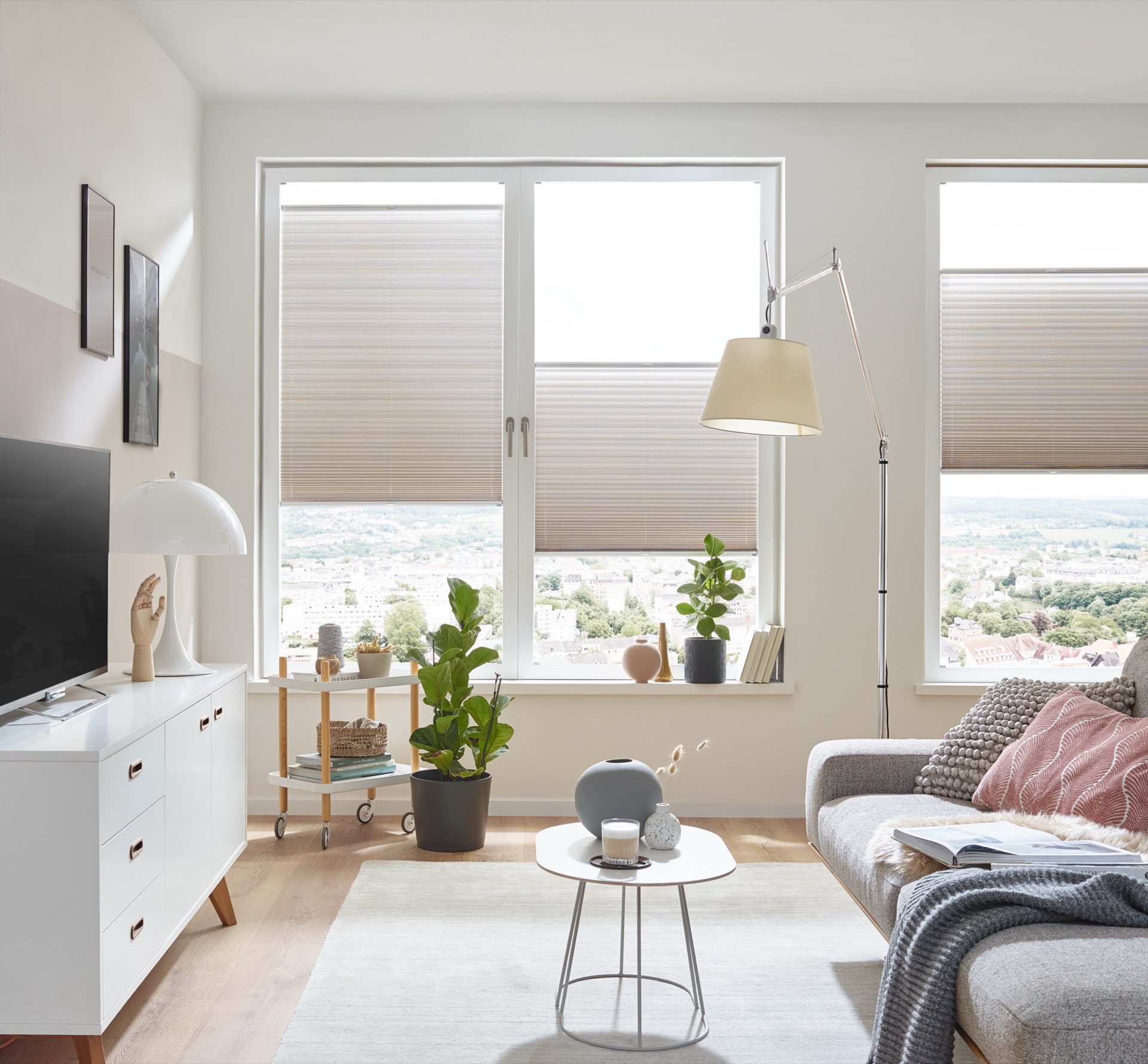 Halbtransparentes Plissee mit reflektierender Rückseite am besonnten Fenster