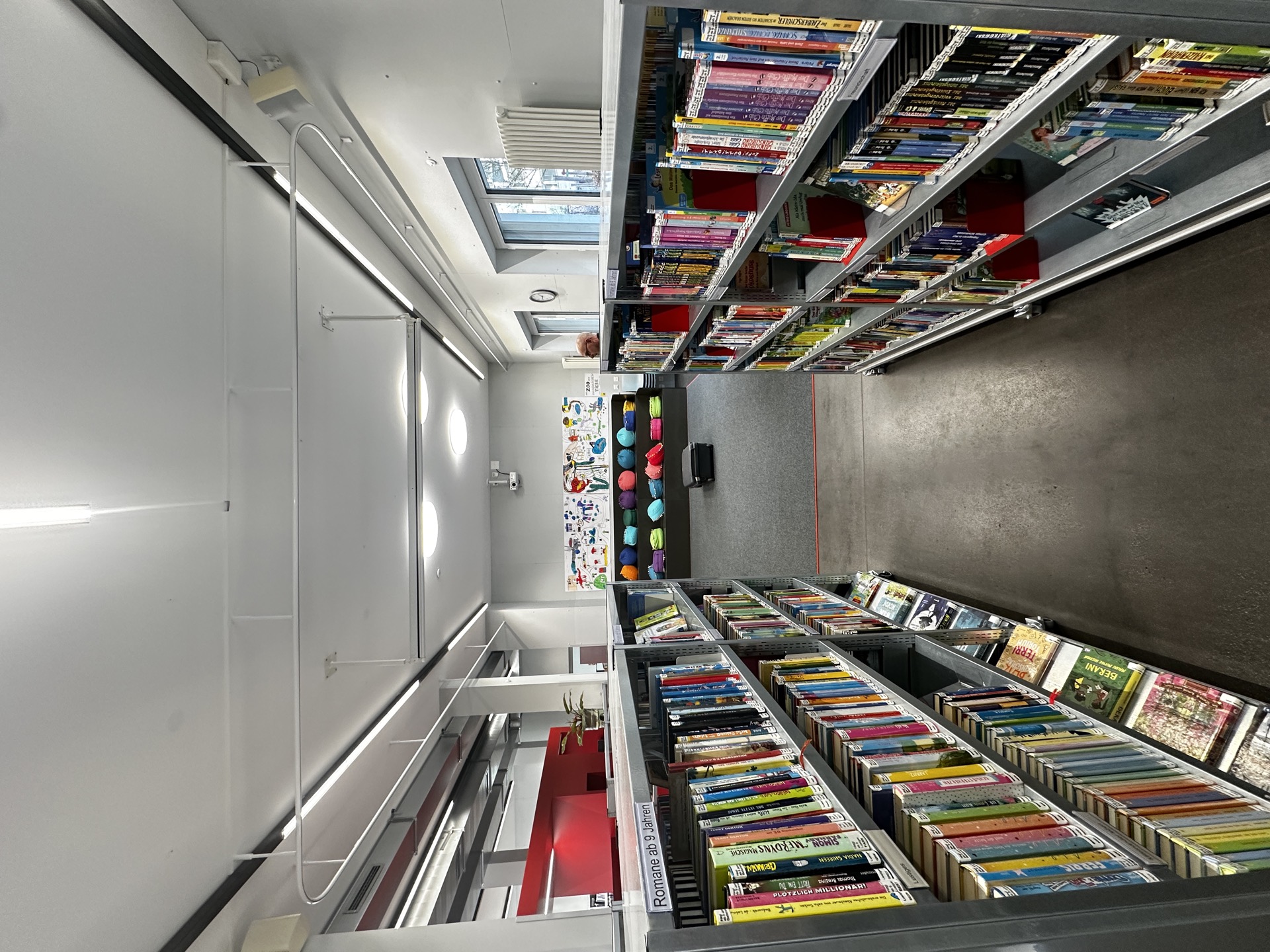 Bibliothek mit Bücherregalen und deckenmontierten Vorhangschienen entlang der Fensterfront