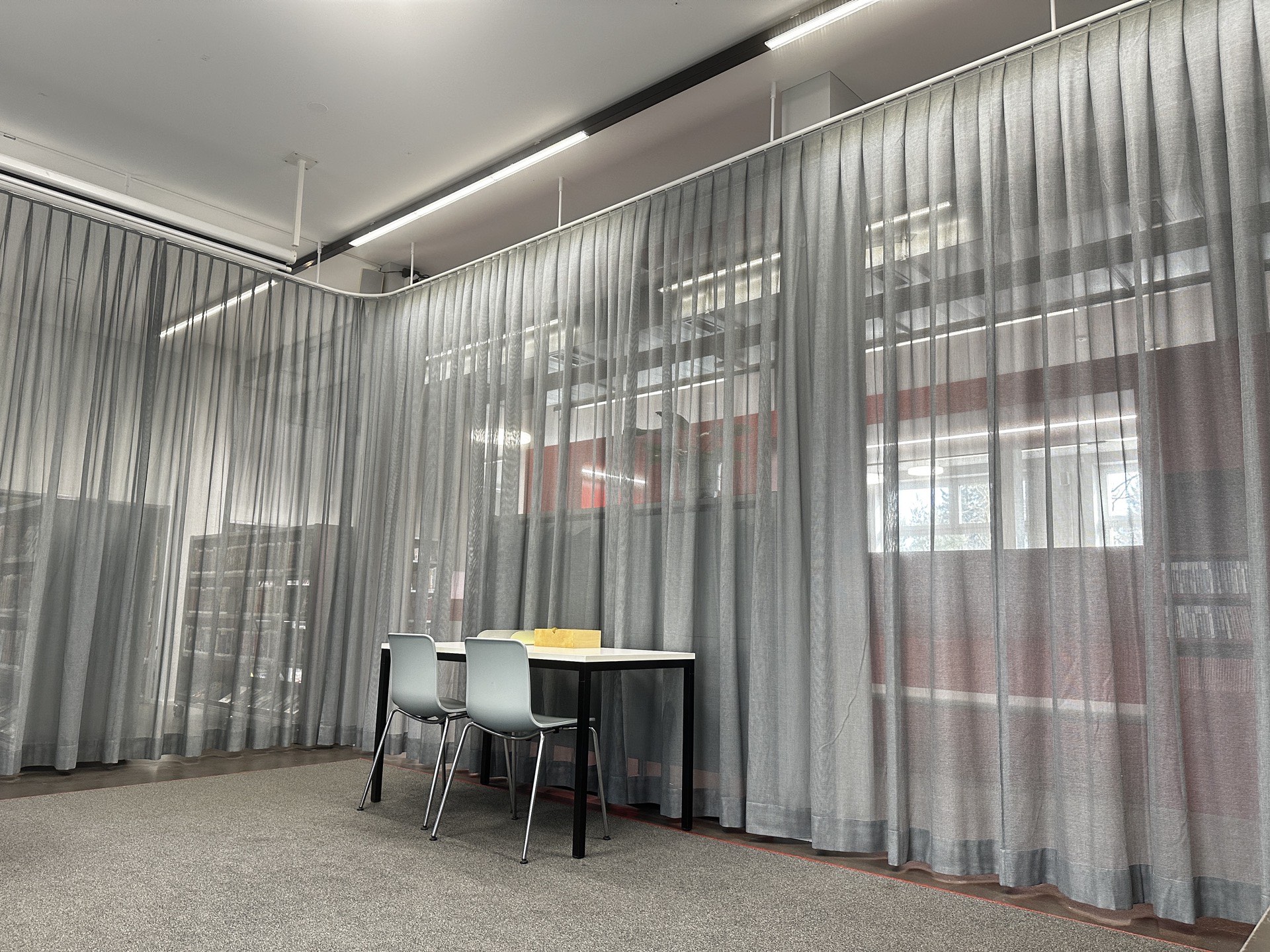 Transparente graue Flächenvorhänge an deckenmontierter Schiene in der Bibliothek