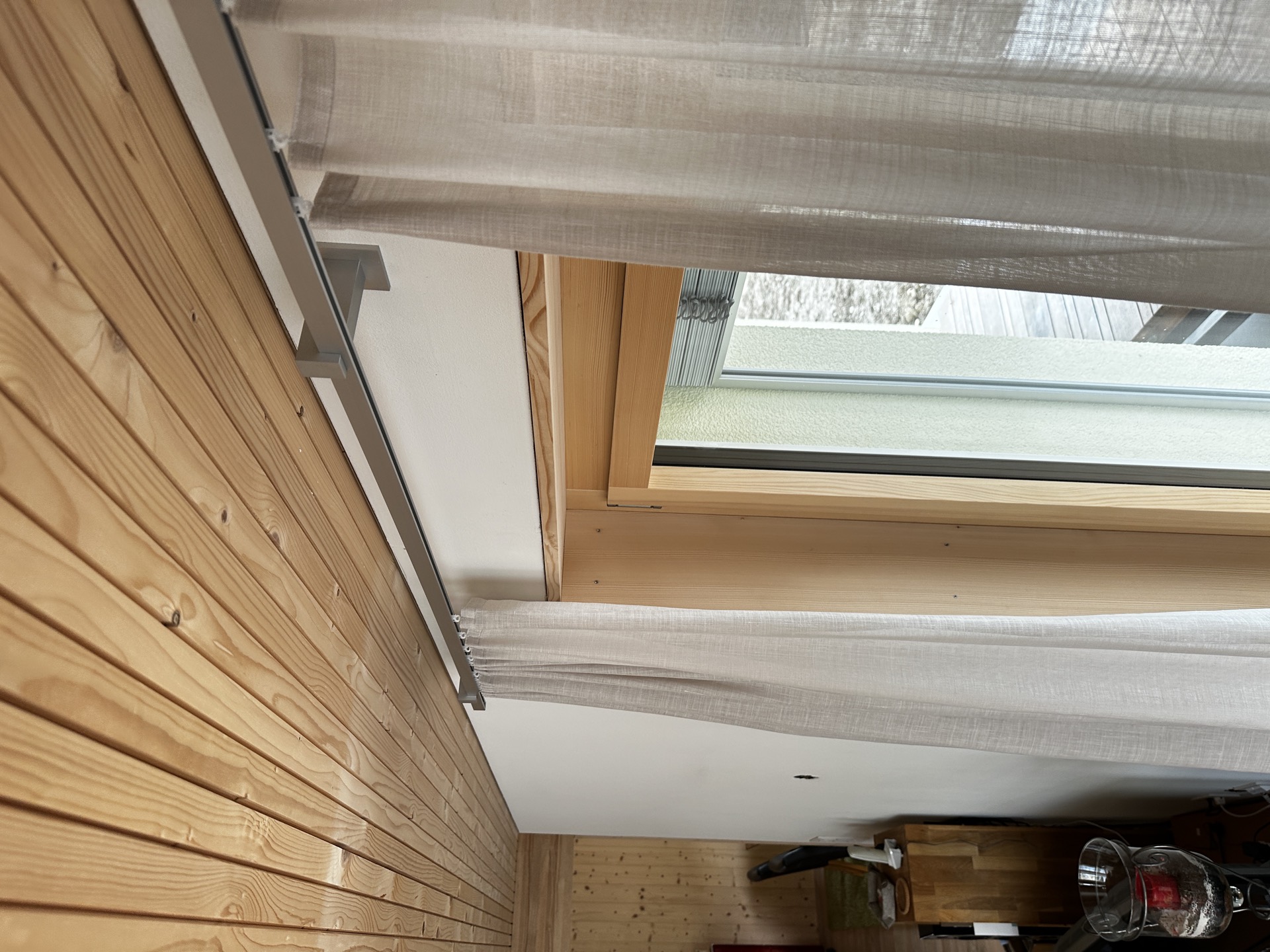 Transparenter Tagesvorhang an der Schiene über der Fenstertür im Holzchalet
